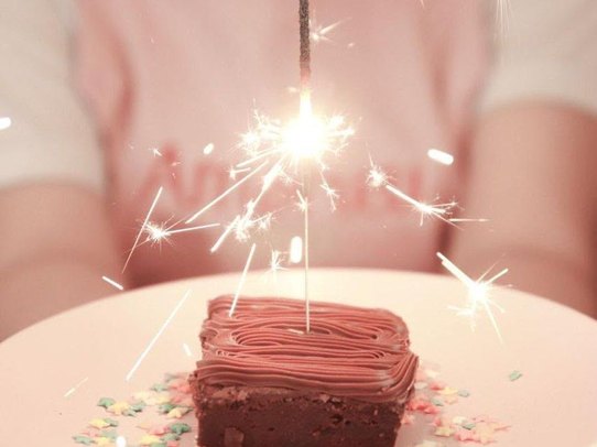 Fatia de bolo com vela de faísca nas mãos